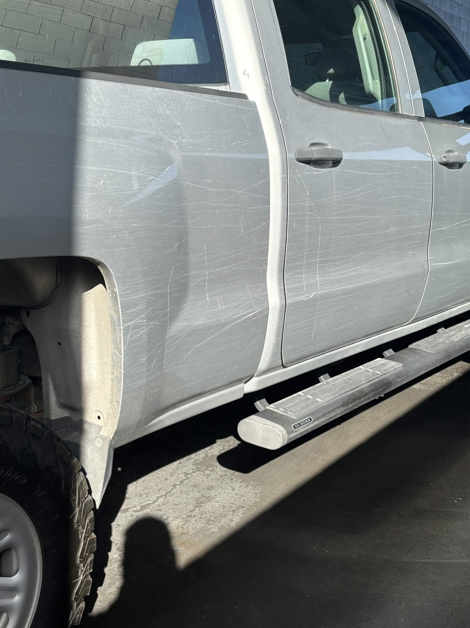Silver pickup truck side with heavy trail scratches before detailing