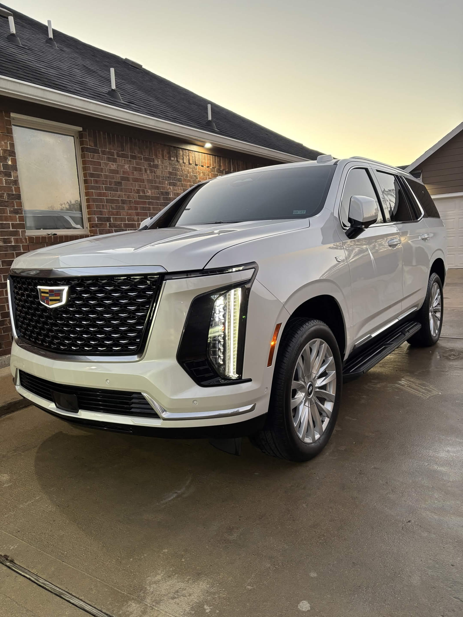 White Cadillac Escalade with wet driveway after wash