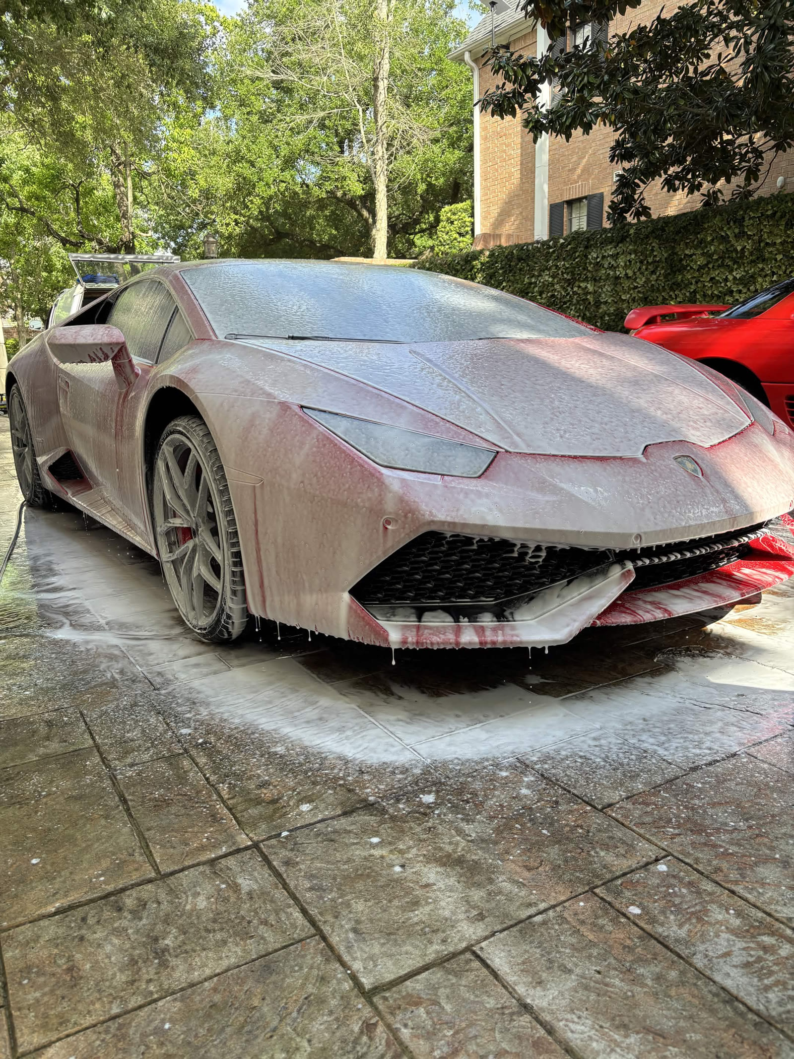 Red Lamborghini Huracán covered in snow foam during wash